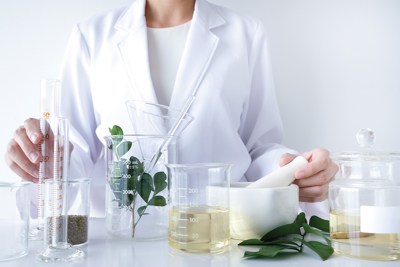 scientist in white lab coat behind vials and plants - nature and science meet