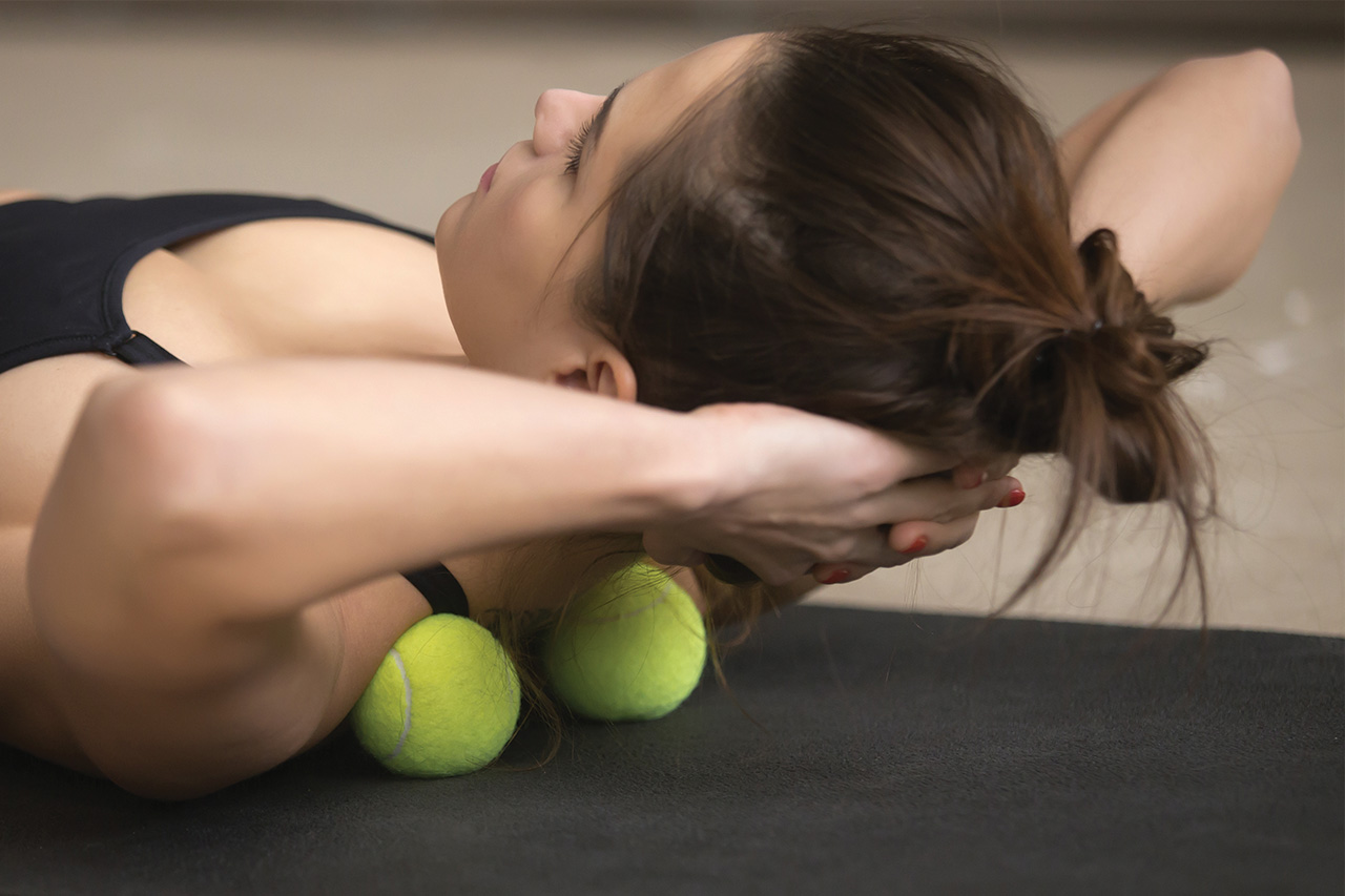 woman exercising her neck on 2 tennis balls