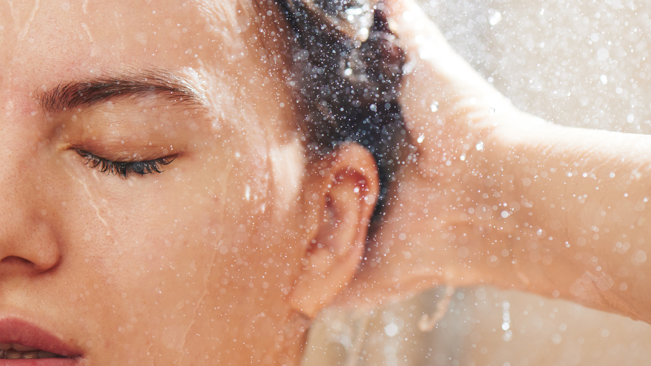 closeup of white woman splashing water on her face and hair